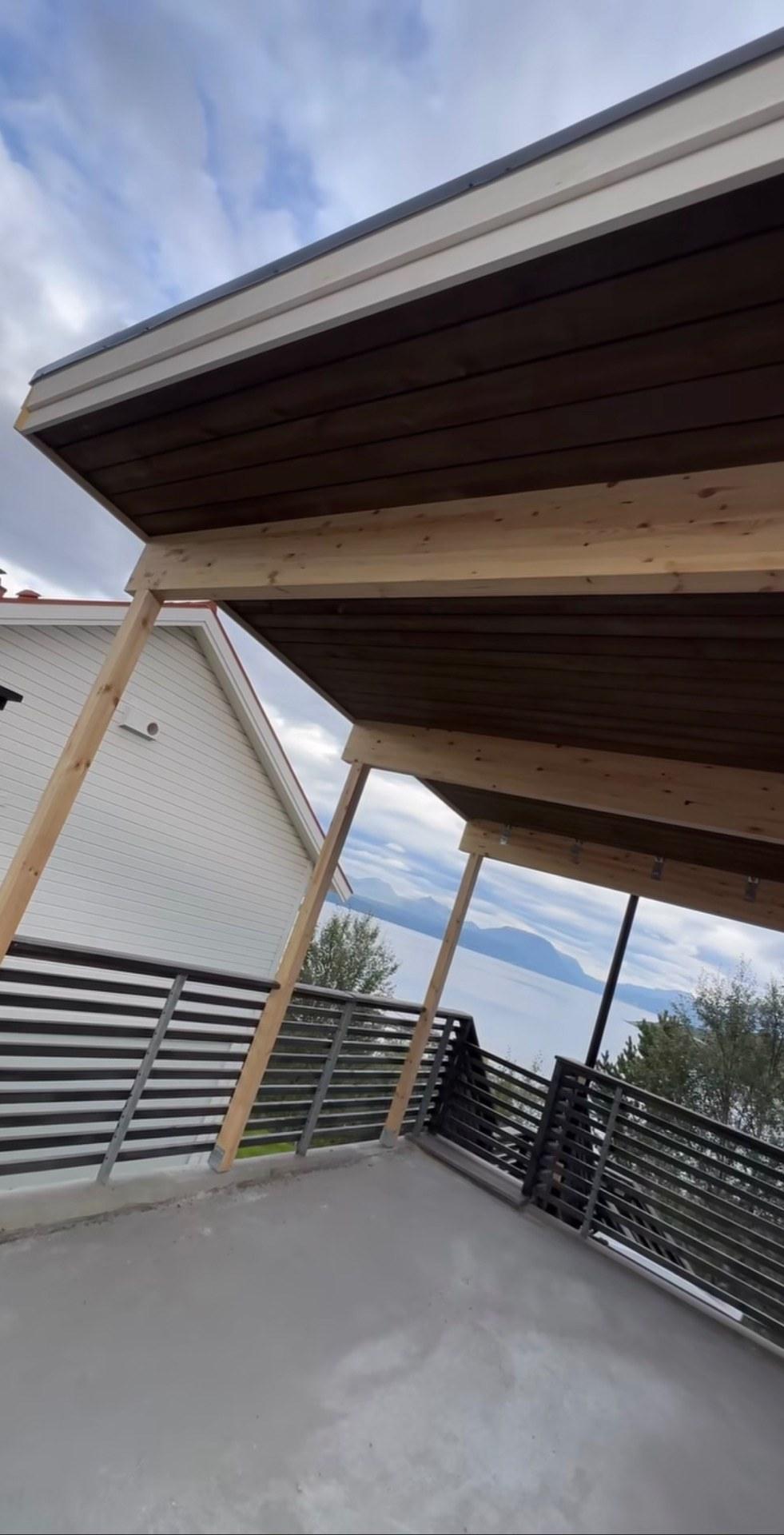 Overbygd terrasse med rekkverk og utsikt over fjellene