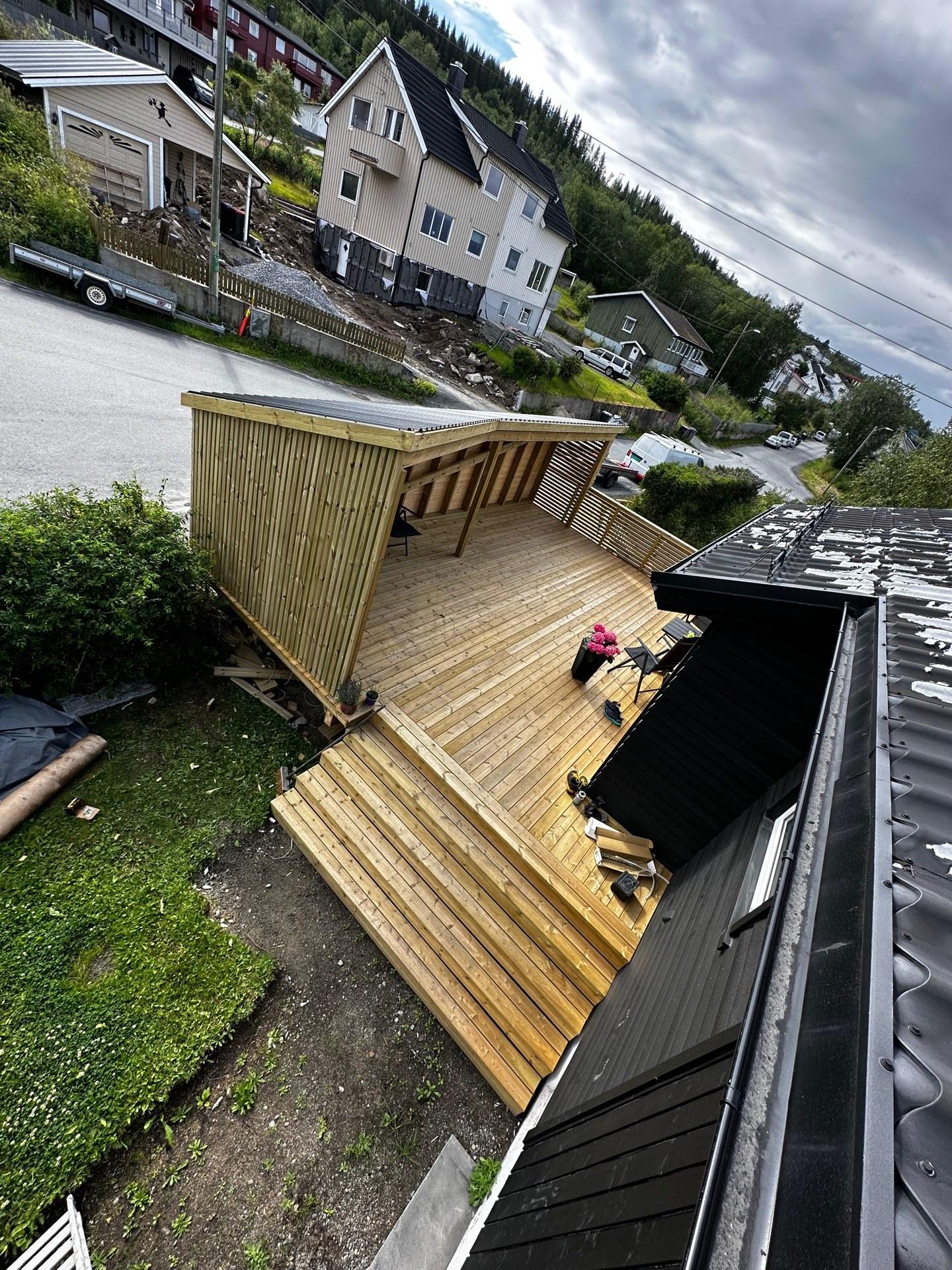 Ny trapp og terrasse i trykkimpregnert tre ved en svart enebolig